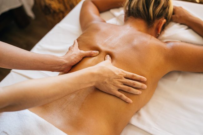 a person massaging a client s bare back
